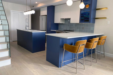 高級な中くらいなモダンスタイルのおしゃれなアイランドキッチン (青いキャビネット、青いキッチンパネル、セラミックタイルのキッチンパネル、シルバーの調理設備、淡色無垢フローリング) の写真