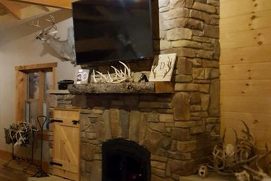 Imagen de sala de estar abierta rústica de tamaño medio con suelo de madera clara, todas las chimeneas, marco de chimenea de piedra y televisor colgado en la pared