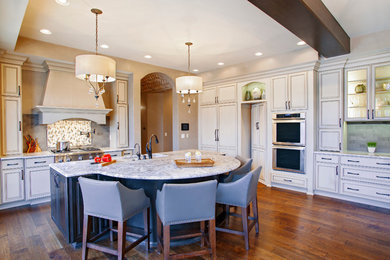 Mid-sized elegant l-shaped medium tone wood floor eat-in kitchen photo in Denver with an undermount sink, recessed-panel cabinets, beige cabinets, multicolored backsplash, mosaic tile backsplash, stainless steel appliances, an island and granite countertops