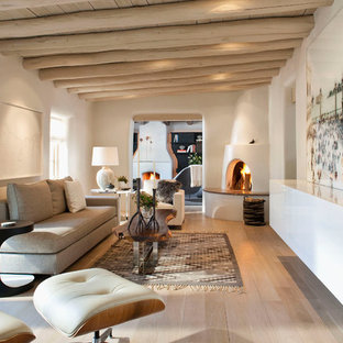 Mittelgroßes, Abgetrenntes Mediterranes Wohnzimmer mit Eckkamin, weißer Wandfarbe, hellem Holzboden und verputztem Kaminsims in Albuquerque