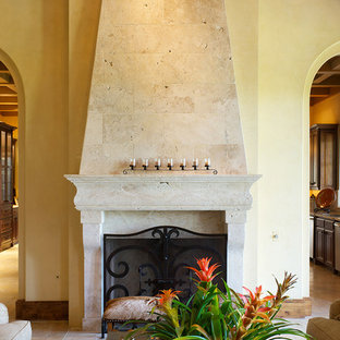 Foto de salón para visitas abierto, mediterráneo, con paredes beige, suelo de piedra caliza, chimenea tradicional y marco de chimenea de piedra