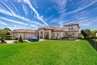 Example of a large tuscan beige two-story stucco house exterior design in Orlando with a tile roof