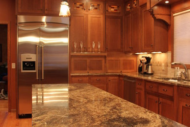 This is an example of a large arts and crafts l-shaped eat-in kitchen in Minneapolis with a double-bowl sink, recessed-panel cabinets, medium wood cabinets, granite benchtops, beige splashback, stainless steel appliances and medium hardwood floors.