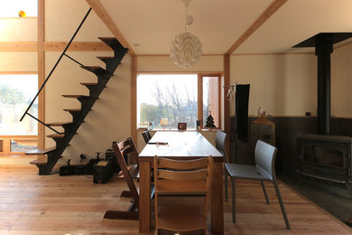 Photo of an asian dining room in Other with a wood stove and a concrete fireplace surround.