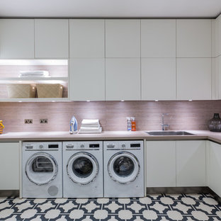 This is an example of a medium sized contemporary u-shaped utility room in London with an integrated sink, flat-panel cabinets, white cabinets, laminate countertops, white walls, porcelain flooring, a side by side washer and dryer, multi-coloured floors and brown worktops.
