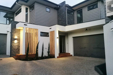 Inspiration for a mid-sized contemporary two-storey multi-coloured townhouse exterior in Melbourne with concrete fiberboard siding, a hip roof, a metal roof, a black roof and board and batten siding.