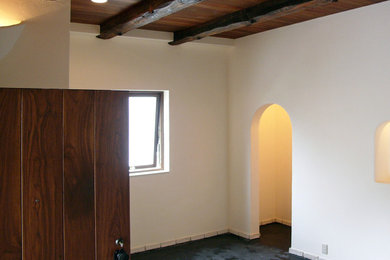 他の地域にあるラスティックスタイルのおしゃれな玄関ホール (白い壁、コンクリートの床、茶色いドア、黒い床、白い天井) の写真
