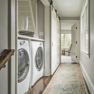 This is an example of a small farmhouse single-wall laundry cupboard in Boston with shaker cabinets, white cabinets, wood worktops, grey walls, a side by side washer and dryer and white worktops.