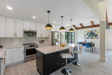 Inspiration for a mid-sized contemporary l-shaped vinyl floor, gray floor and exposed beam eat-in kitchen remodel in DC Metro with a drop-in sink, shaker cabinets, black cabinets, quartzite countertops, white backsplash, subway tile backsplash, stainless steel appliances, an island and white countertops
