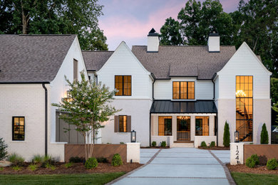 Example of a large minimalist white two-story brick house exterior design in Charlotte with a shingle roof and a gray roof