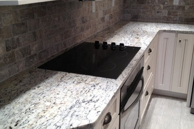 Mid-sized u-shaped vinyl floor kitchen photo in Miami with beaded inset cabinets, white cabinets, granite countertops, multicolored backsplash, brick backsplash and stainless steel appliances