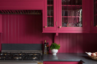 Inspiration for a small classic l-shaped enclosed kitchen in Seattle with a belfast sink, shaker cabinets, pink cabinets, granite worktops, pink splashback, wood splashback, integrated appliances, light hardwood flooring, no island, brown floors and black worktops.