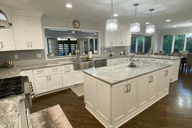 Eat-in kitchen - large transitional u-shaped dark wood floor and brown floor eat-in kitchen idea in Detroit with a farmhouse sink, shaker cabinets, white cabinets, granite countertops, gray backsplash, subway tile backsplash, stainless steel appliances, an island and multicolored countertops