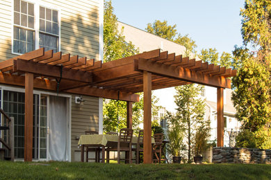 Mid-sized trendy backyard brick patio photo in Boston with a pergola