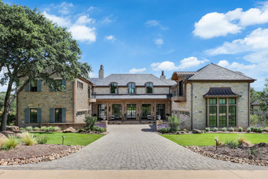 French country beige two-story exterior home idea in Houston with a hip roof, a shingle roof and a gray roof