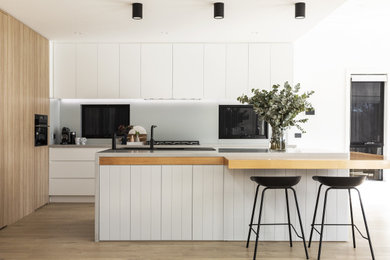 Modern kitchen in Sydney with a drop-in sink, raised-panel cabinets, grey cabinets, quartz benchtops, grey splashback, laminate floors and grey benchtop.