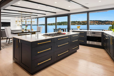 Inspiration for a large contemporary u-shaped eat-in kitchen in Seattle with an undermount sink, recessed-panel cabinets, black cabinets, marble benchtops, stainless steel appliances, light hardwood floors, with island, brown floor and white benchtop.