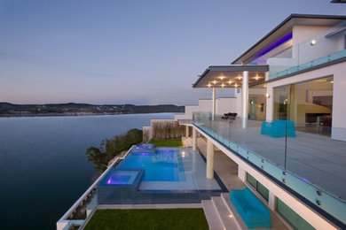 Design ideas for an expansive contemporary backyard rectangular infinity pool in Austin with natural stone pavers.