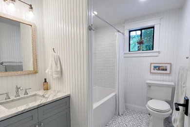Photo of a mid-sized traditional bathroom in Boston with shaker cabinets, blue cabinets, a shower/bathtub combo, white tile, subway tile, white walls, marble floors, marble benchtops, a shower curtain, a single vanity, a built-in vanity and decorative wall panelling.