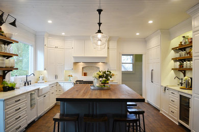This is an example of a large contemporary u-shaped eat-in kitchen in Denver with a farmhouse sink, white cabinets, wood benchtops, white splashback, ceramic splashback, white appliances, dark hardwood floors, with island, brown floor and red benchtop.