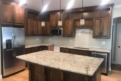 Example of a classic l-shaped enclosed kitchen design in Charlotte with an undermount sink, granite countertops, stainless steel appliances and an island