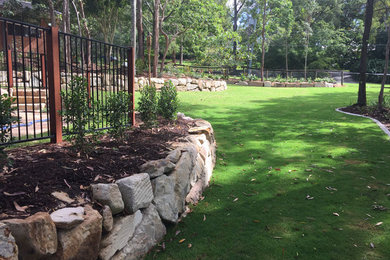 Expansive backyard partial sun garden in Gold Coast - Tweed with a retaining wall and mulch.