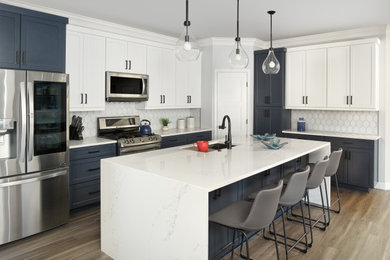 Eat-in kitchen - mid-sized transitional l-shaped laminate floor and gray floor eat-in kitchen idea in Dallas with an undermount sink, shaker cabinets, white cabinets, quartz countertops, white backsplash, glass tile backsplash, stainless steel appliances, an island and white countertops