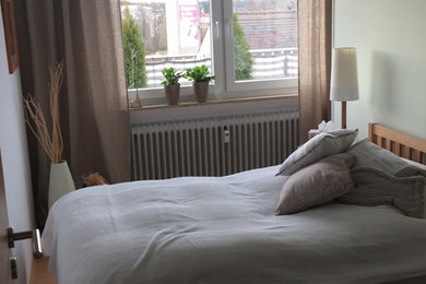 This is an example of a small country guest bedroom in Frankfurt with white walls, light hardwood floors, no fireplace and beige floor.