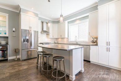 Large transitional medium tone wood floor eat-in kitchen photo in Vancouver with an undermount sink, shaker cabinets, white cabinets, quartz countertops, white backsplash, porcelain backsplash, stainless steel appliances and an island