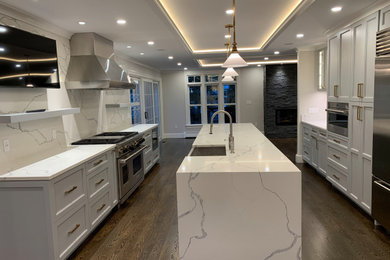 Design ideas for a large transitional galley separate kitchen in Boston with a farmhouse sink, raised-panel cabinets, quartzite benchtops, white splashback, stone slab splashback, stainless steel appliances, dark hardwood floors, with island, brown floor, white benchtop and grey cabinets.