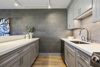 Small minimalist galley vinyl floor and brown floor kitchen photo in San Francisco with a single-bowl sink, recessed-panel cabinets, quartzite countertops, gray backsplash, porcelain backsplash, black appliances, an island and white countertops