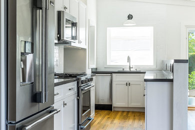 Small transitional u-shaped medium tone wood floor and brown floor kitchen photo in Orange County with an undermount sink, shaker cabinets, white cabinets, quartzite countertops, white backsplash, ceramic backsplash, stainless steel appliances and no island