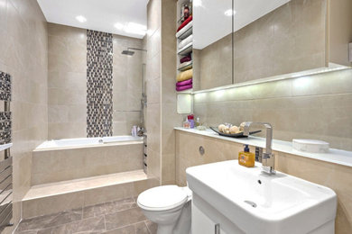 Inspiration for a medium sized modern family bathroom in London with freestanding cabinets, beige cabinets, a built-in bath, a built-in shower, a wall mounted toilet, multi-coloured tiles, marble tiles, a wall-mounted sink, marble worktops, a hinged door, white worktops, a single sink and a built in vanity unit.