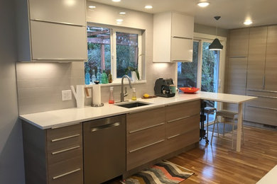 Design ideas for a small contemporary galley eat-in kitchen in Seattle with an undermount sink, flat-panel cabinets, white cabinets, quartz benchtops, white splashback, ceramic splashback, stainless steel appliances, light hardwood floors and no island.