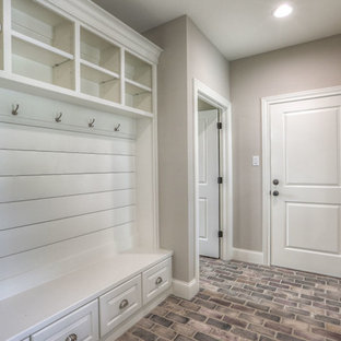 ヒューストンの中サイズの片開きドアトランジショナルスタイルのおしゃれなマッドルーム (ベージュの壁、レンガの床、白いドア、ベージュの床) の写真