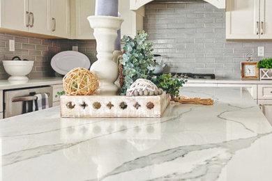 Inspiration for a transitional kitchen remodel in Chicago with recessed-panel cabinets, white cabinets, quartzite countertops, gray backsplash, subway tile backsplash, stainless steel appliances, an island and white countertops