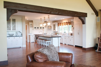Inspiration for a large rustic l-shaped medium tone wood floor kitchen remodel in Cincinnati with a farmhouse sink, beaded inset cabinets, white cabinets, granite countertops, white backsplash, subway tile backsplash, stainless steel appliances and an island