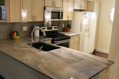 Example of a mid-sized transitional l-shaped dark wood floor and brown floor enclosed kitchen design in Phoenix with an undermount sink, shaker cabinets, light wood cabinets, granite countertops, beige backsplash, stone slab backsplash, stainless steel appliances and a peninsula