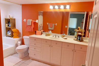 Example of a large beach style kids' orange tile ceramic tile, multicolored floor, single-sink and wallpaper drop-in bathtub design in Orlando with beaded inset cabinets, white cabinets, a two-piece toilet, orange walls, laminate countertops and a built-in vanity