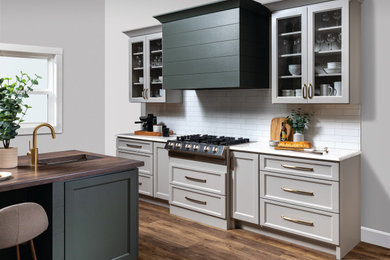 Modelo de cocina clásica renovada con armarios con paneles lisos, puertas de armario beige, salpicadero blanco, salpicadero de azulejos tipo metro y encimeras blancas