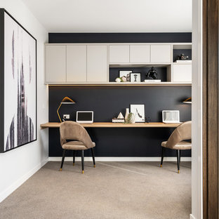 This is an example of a contemporary home office in Melbourne with black walls, carpet, a built-in desk and beige floor.