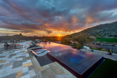 Inspiration for a large contemporary backyard stone and custom-shaped infinity pool landscaping remodel in Phoenix