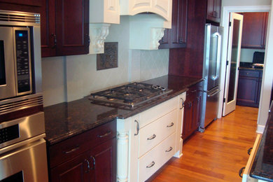 Large traditional galley eat-in kitchen in Seattle with beaded inset cabinets, dark wood cabinets, granite benchtops, beige splashback, porcelain splashback, stainless steel appliances, medium hardwood floors and with island.