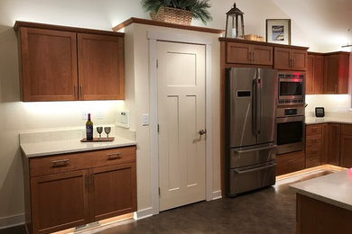 Mid-sized transitional u-shaped multicolored floor eat-in kitchen photo in Other with an undermount sink, shaker cabinets, medium tone wood cabinets, quartz countertops, white backsplash and stainless steel appliances