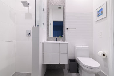 Example of a minimalist porcelain tile porcelain tile, gray floor and single-sink bathroom design in Miami with flat-panel cabinets, white cabinets, a one-piece toilet, white walls, white countertops and a floating vanity