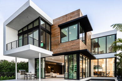 Inspiration for a large contemporary two-storey white house exterior in Miami with wood siding and a flat roof.