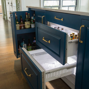 Diseño de cocina de galera, actual, pequeña, abierta, con fregadero bajoencimera, armarios estilo shaker, puertas de armario blancas, encimera de acrílico, salpicadero blanco, salpicadero de azulejos de cemento, electrodomésticos de acero inoxidable, suelo de madera en tonos medios, una isla y suelo marrón