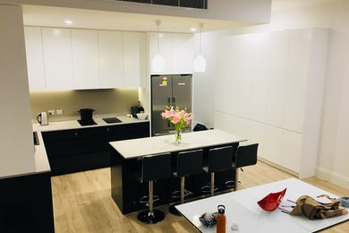 Photo of a mid-sized l-shaped kitchen in Sydney with a double-bowl sink, shaker cabinets, white cabinets, quartz benchtops, beige splashback, stone slab splashback, stainless steel appliances, with island and white benchtop.