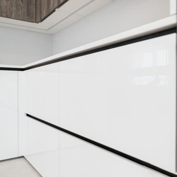 Современная серо-белая кухня в высокими шкафами и барной стойкой