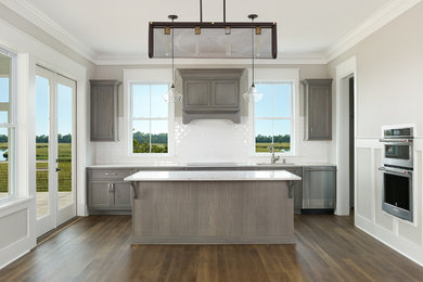Design ideas for a transitional kitchen in Charleston with a drop-in sink, shaker cabinets, distressed cabinets, quartz benchtops, white splashback, ceramic splashback, stainless steel appliances, medium hardwood floors, with island, brown floor and white benchtop.